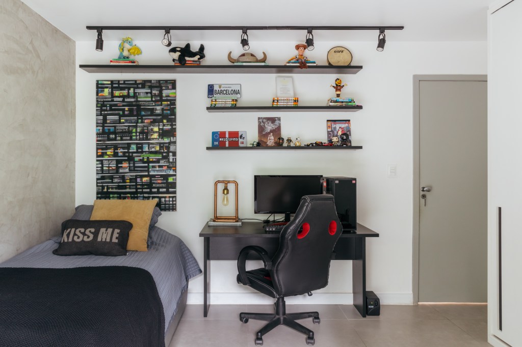 Apartamento de 140 m² parece uma casa em meio às árvores. Projeto Ana Cano. Na foto, quarto infantil com cadeira gamer e parede de cimento queimado.