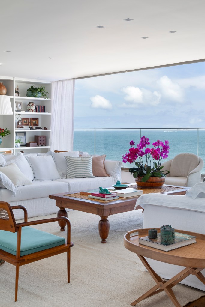 Apê de 250m² tem cozinha com três cubas e balcão de mármore verde. Projeto de Escala Arquitetura. Na foto, sala de estar com sofá branco e vista para o mar.