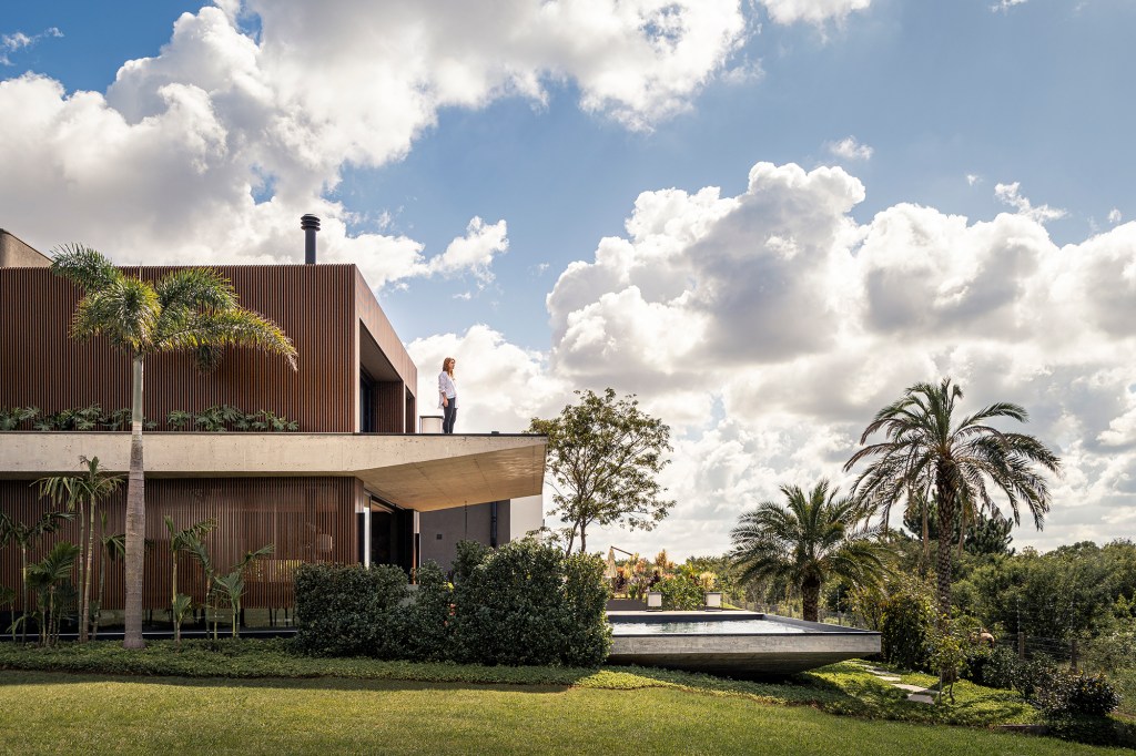 A água é destaque nesta casa de 457 m² no Rio Grande do Sul. Projeto de Stemmer Rodrigues. Na foto, fachada com jardim e piscina.