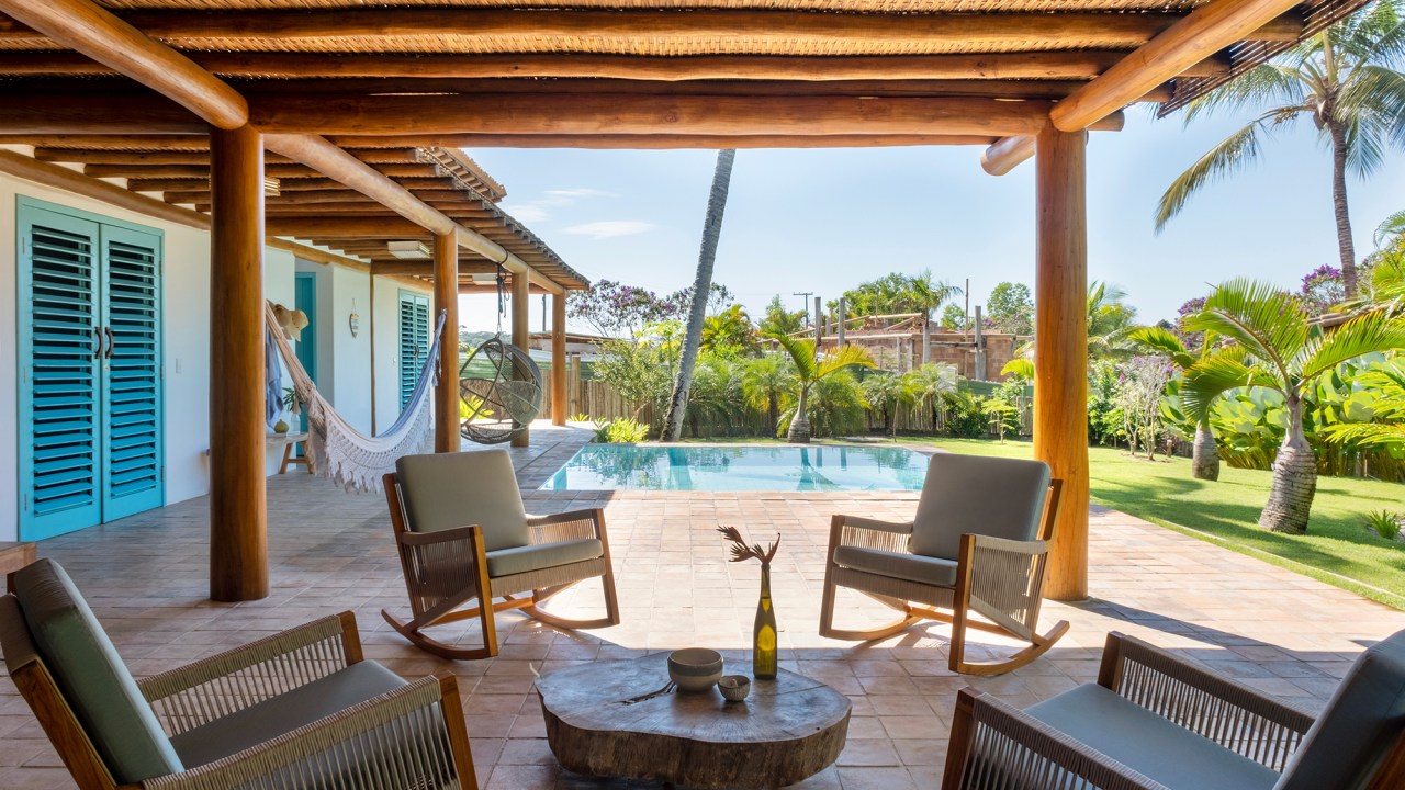 Casa em Trancoso é inspirada na arquitetura colonial do sul da Bahia. Projeto Conrado Ceravolo. Na foto, piscina com poltrona suspensa e banco. Varanda com pergolado.