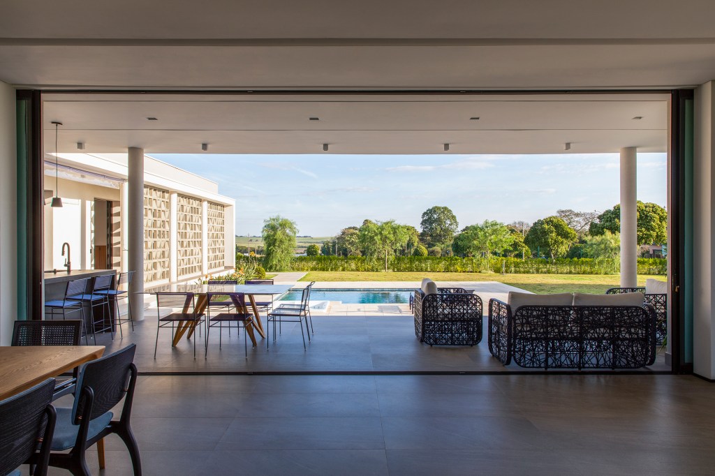 Fachada de cobogós cria efeito cênico nesta casa no interior de São Paulo. Projeto de Starq, Na foto, fachada da casa com piscina e jardim.