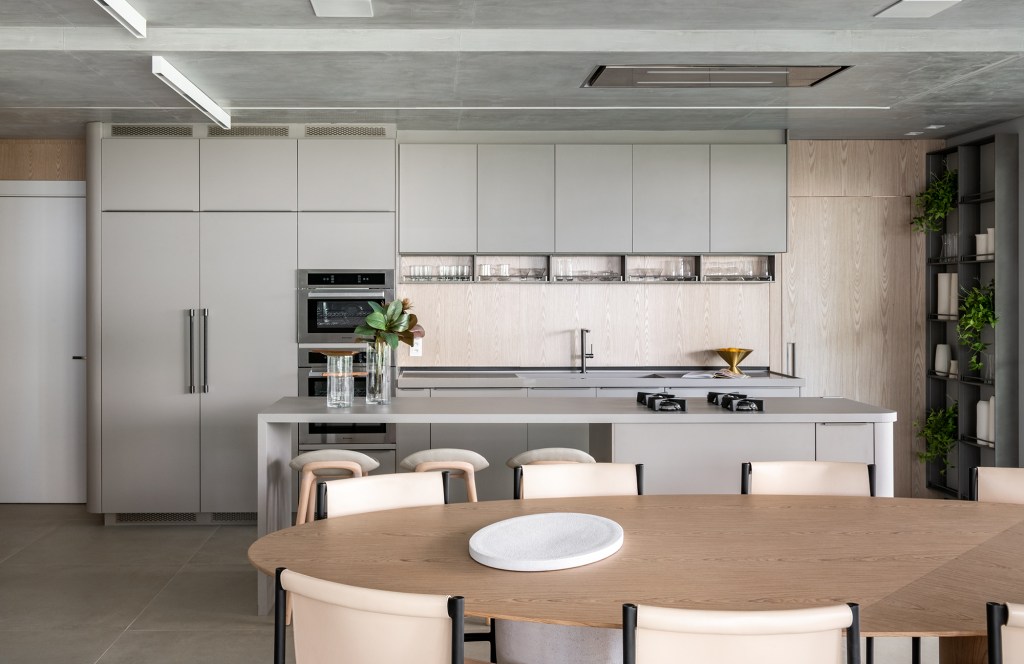 Formas orgânicas e tons neutros criam aconchego neste apê de 190 m². Projeto de Bohrer Arquitetos. Na foto, cozinha com ilha e móveis cinzas.