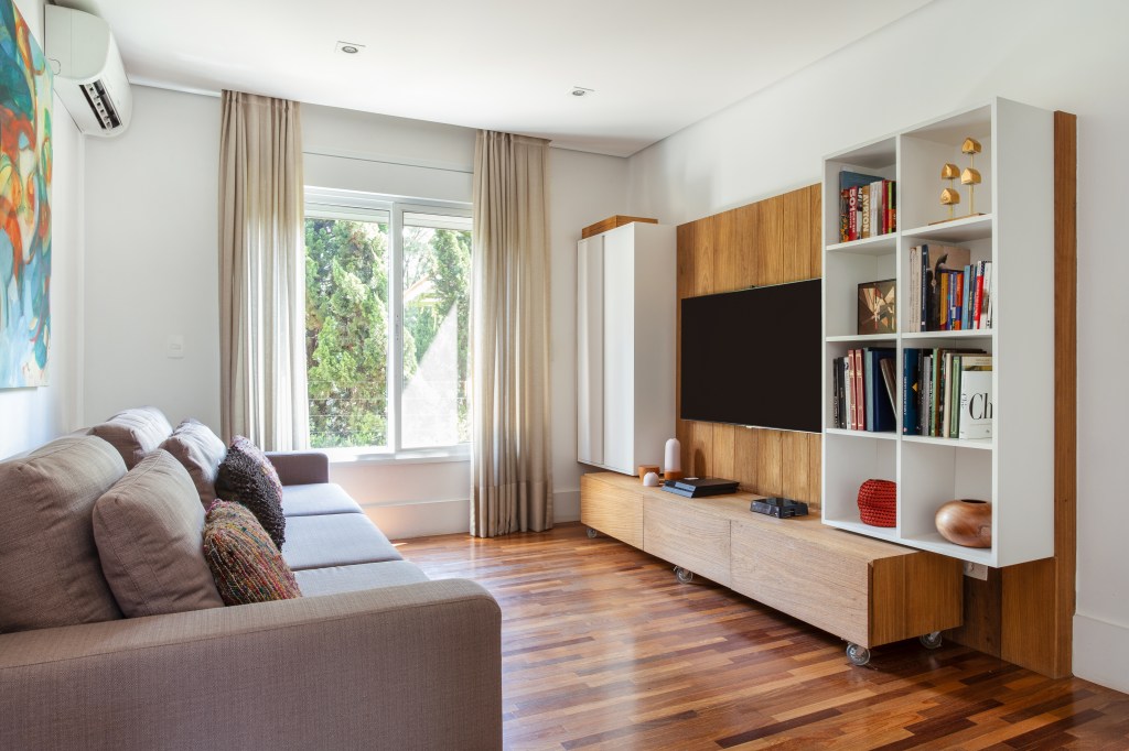 casa-piscina-varanda-gourmet-sala-intima-videogames-jogos-dantas-e-passos-arquitetura-18 Casa com piscina e varanda gourmet tem sala íntima para videogames e jogos. Projeto de Dantas & Passos Arquitetura. Na foto, sala íntima com estante de jogos de tabuleiro, piso de madeira, sofá e tv.