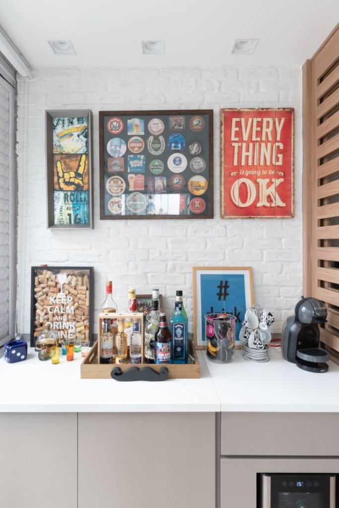 painel-tv-giratoria-divide-sala-home-office-ape-art-2a-credito-julia-herman (5) Painel com TV giratória divide sala de home office neste apê. Projeto de Art 2A Arquitetura. Na foto, bar na varanda, parede de tijolinhos e quadros.