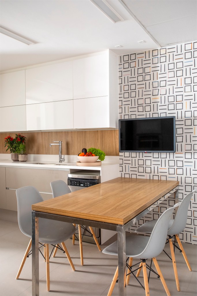 Quarto deste apê tem grande painel de freijó natural com lâminas diagonais. Projeto de Cristina Bezamat. Na foto, cozinha com marcenaria branca, copa de cozinha com parede de azulejos geométricos.