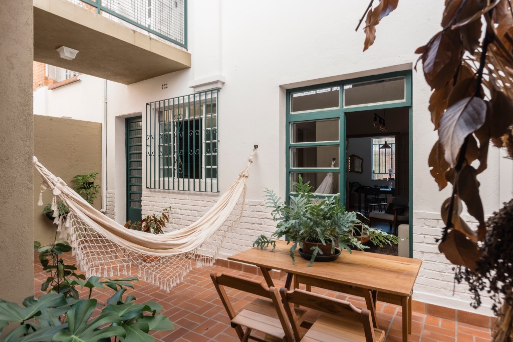 Sobrado de 100 m² ganha solarium e décor que é mix de rústico e retrô. Projeto de Palladino Arquitetura. Na foto, área externa, quintal, rede, mesa de madeira.