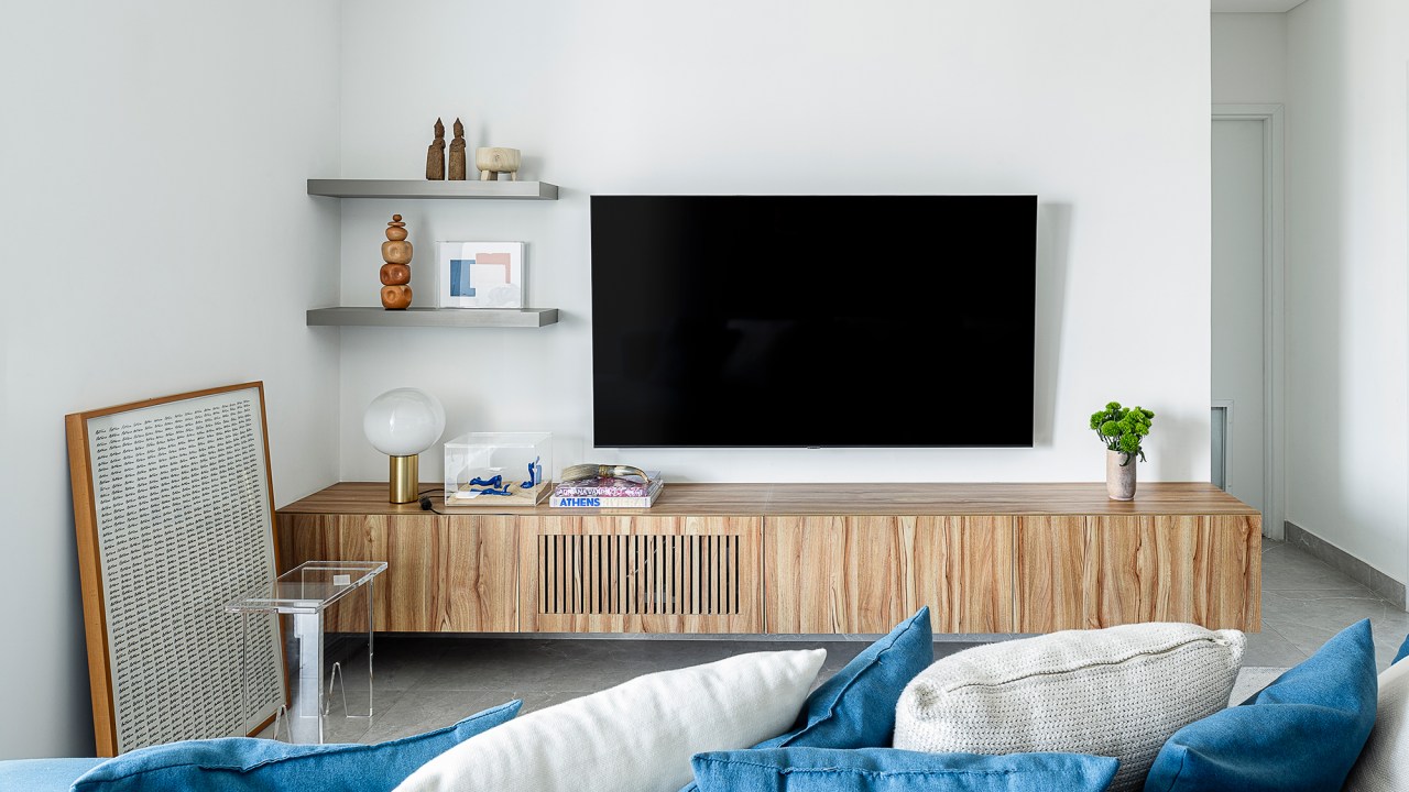 Apartamento de 60 m² ganha décor com tons de azul que remete à praia. Projeto de ETC. Arquitetos. Na foto, sala com varanda, tv e sofá azul.