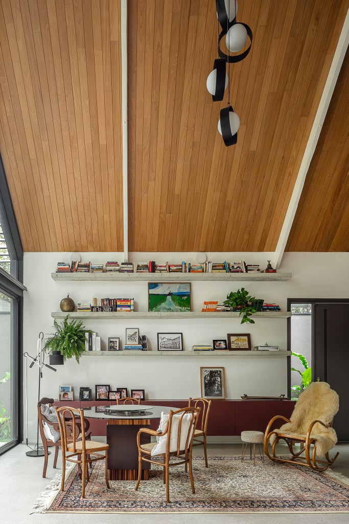 casa-415-m-mezanino-varanda-gourmet-inspirada-chale-alemao-arkitito-arquitetura-03-sala Casa de 415 m² com mezanino e varanda gourmet é inspirada em chalé alemão. Projeto de Arkitito Arquitetura. Na foto, sala de jantar, mesa redonda, prateleiras.