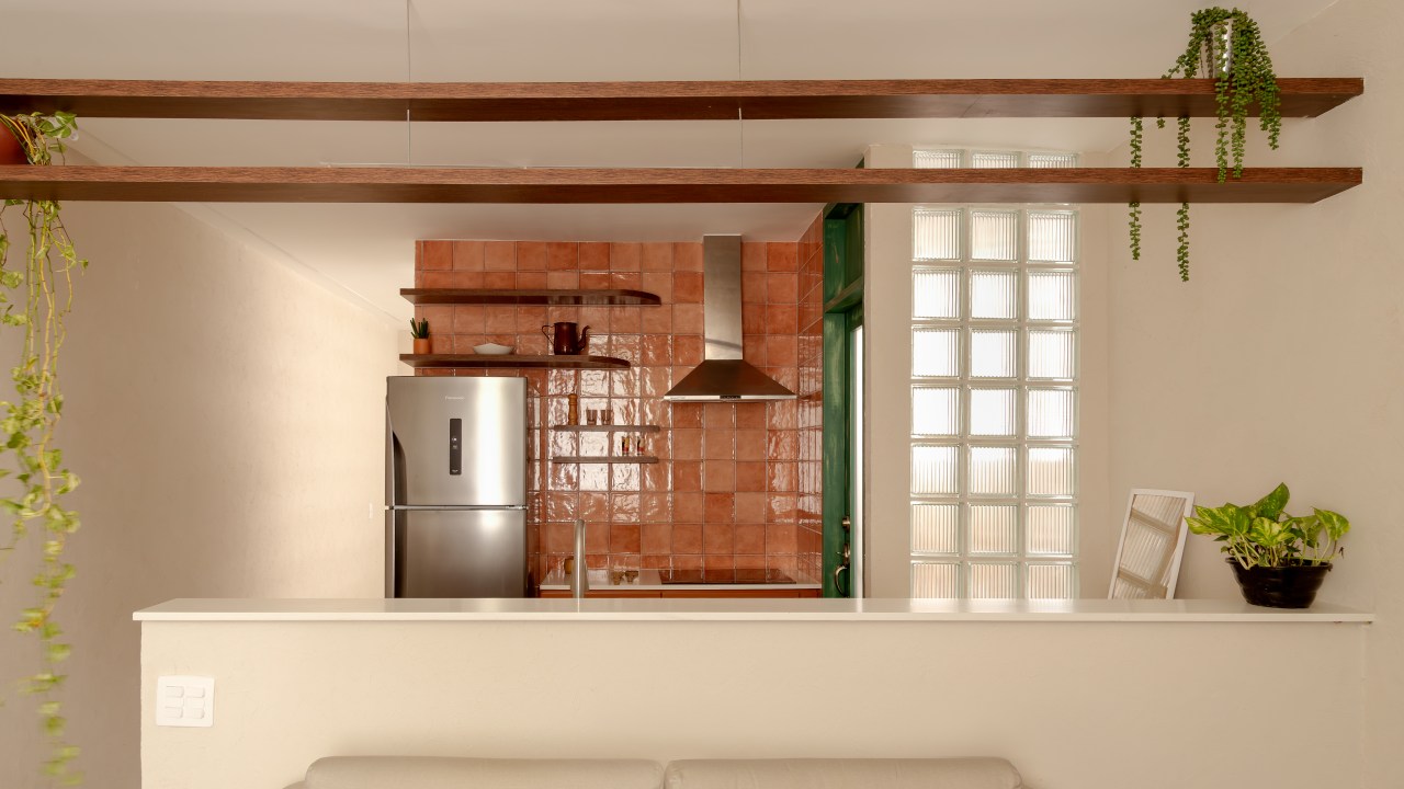Com 33 m², studio com toque vintage usa tijolos de vidro como divisória. Projeto de Mariana Monnerat. Na foto, cozinha com azulejos terracota, porta verde.