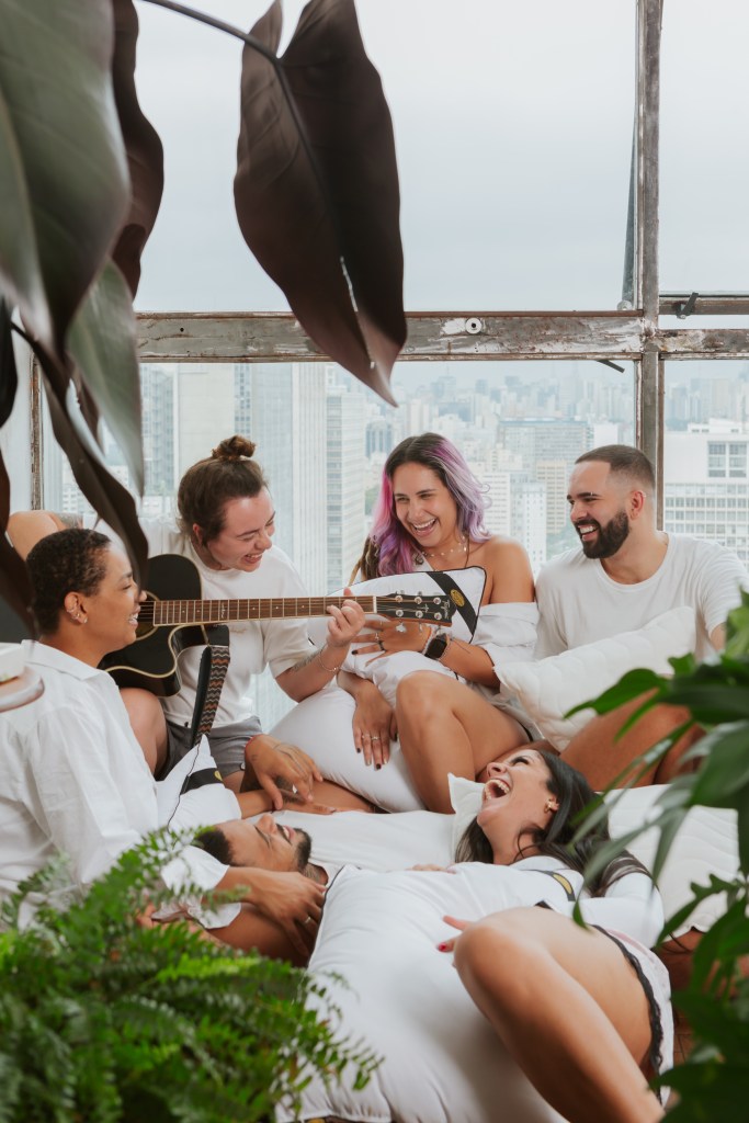 Como a escolha da cama influencia na decoração do quarto. Na foto, grupo de pessoas conversando e sorrindo em quarto.