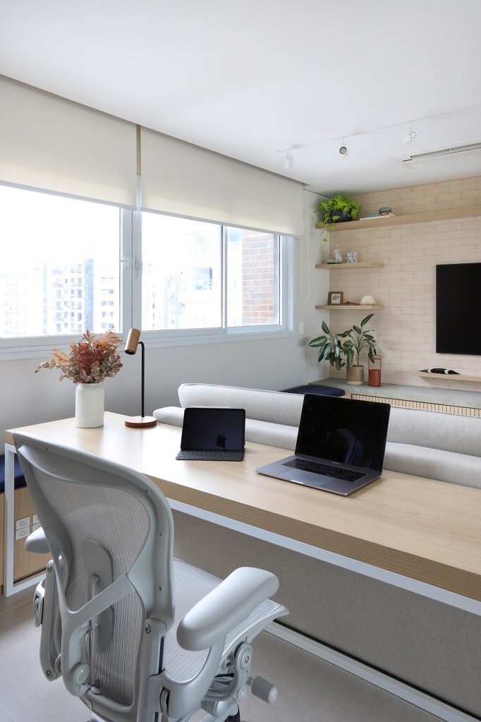 Cozinha verde e espaço para a cachorrinha marcam apê de casal gamer. Projeto de Studio 92 Arquitetura. Na foto. sala com bancada de home office e tv.