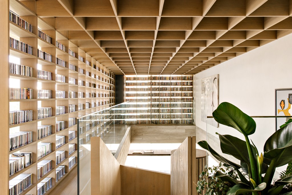 Passarelas com estantes abrigam as coleções do morador deste apê de 420 m²