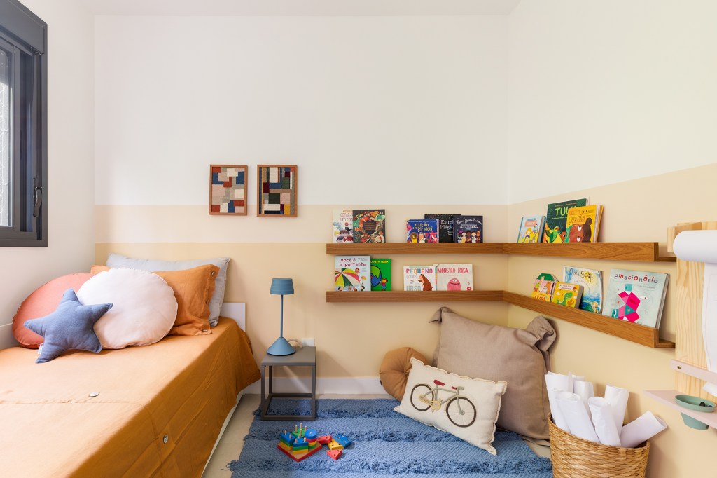 Madeira, conforto e praticidade caracterizam este apartamento de 116 m². Projeto de Studio Canto. Na foto, quarto infantil com prateleiras e tapete.