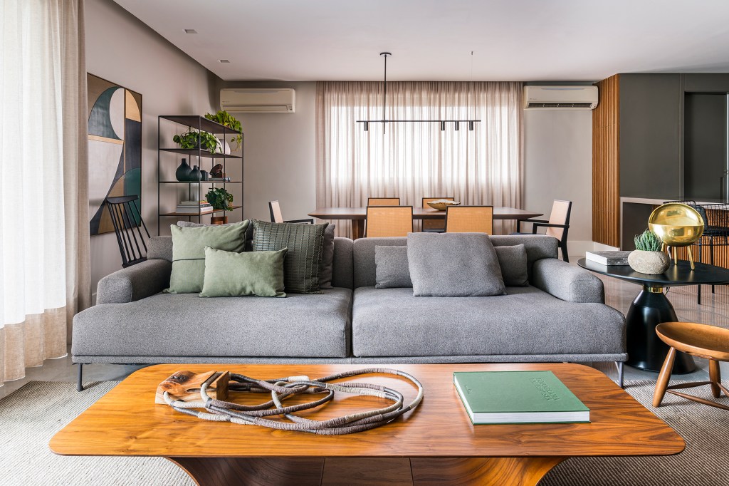 Em um mês, apê alugado de 156 m² ganha projeto contemporâneo e minimalista. Projeto Estúdio Amadas. Na foto, sala com sofá cinza, mesa de jantar e estante.