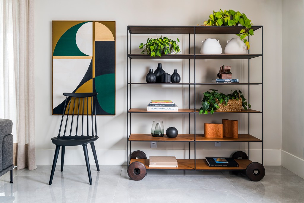 Em um mês, apê alugado de 156 m² ganha projeto contemporâneo e minimalista. Projeto Estúdio Amadas. Na foto, sala com estante vazada, quadro e cadeira,