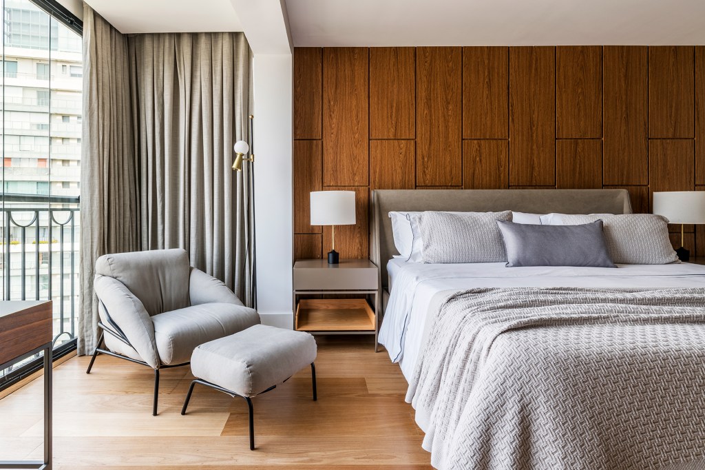 Em um mês, apê alugado de 156 m² ganha projeto contemporâneo e minimalista. Projeto Estúdio Amadas. Na foto, quarto de casal com parede de madeira, tv e abajur,