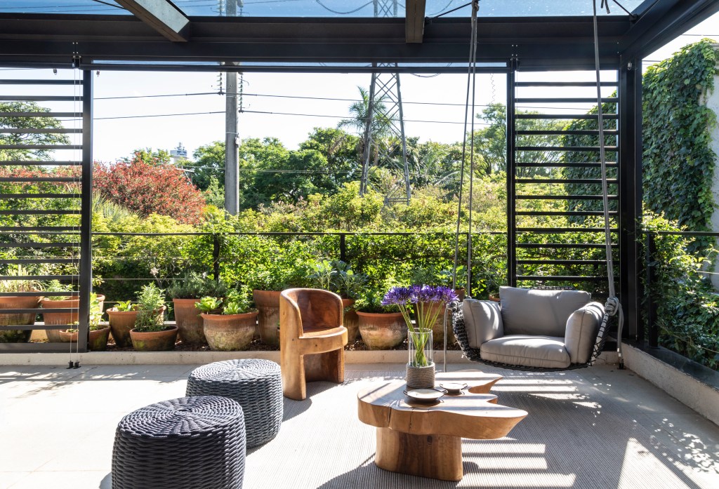 Casa com 400 m² possui suíte com terraço privativo. Projeto de Carolina Gava. Na foto, terraço privativo com uma variedade de móveis