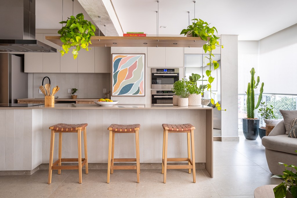 Apê ganha ilha de cozinha espaçosa e brises delimitando sala de TV