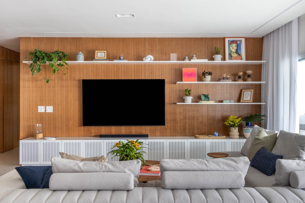 Azulejos pintados à mão com estampas botânicas revestem varanda de apê