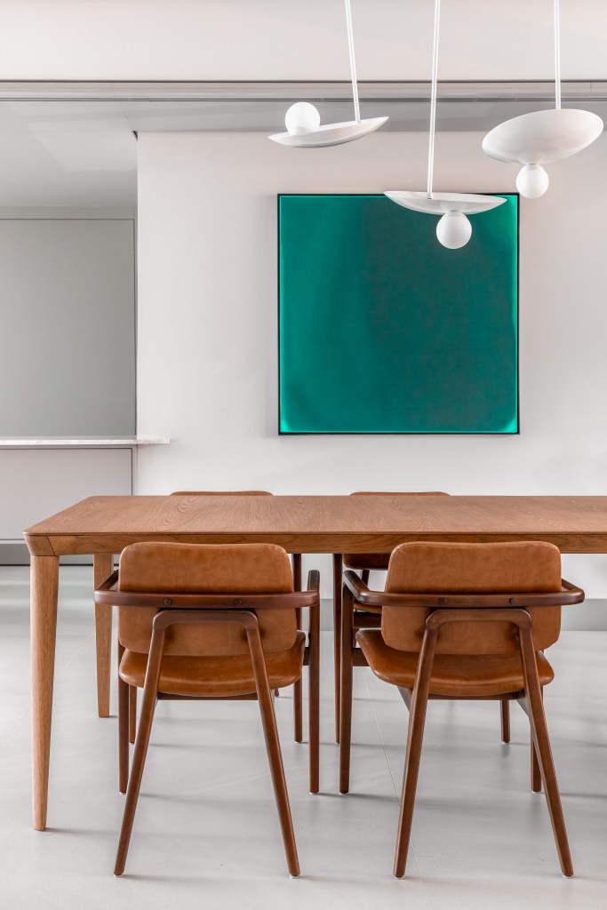 Biblioteca em sala de estar reflete paixão por leitura em apartamento. Projeto de NK Arquitetura. Na foto, sala de jantar, mesa de amdeira, quadro verde.