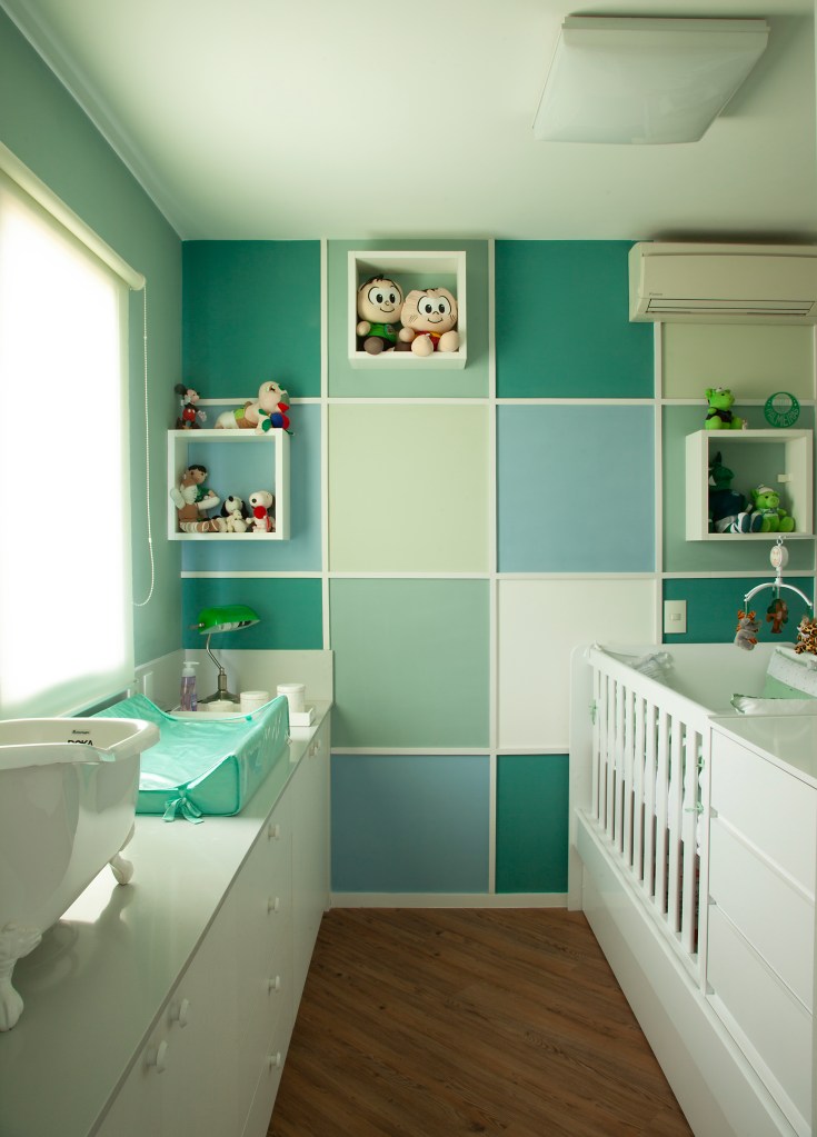 Cozinha de apê tem bancada com 5,6 m em granito e subway tiles no frontão. Projeto de Cristiane Schiavoni. Na foto, quarto de bebê, nichos, berço, parede verde e azul.