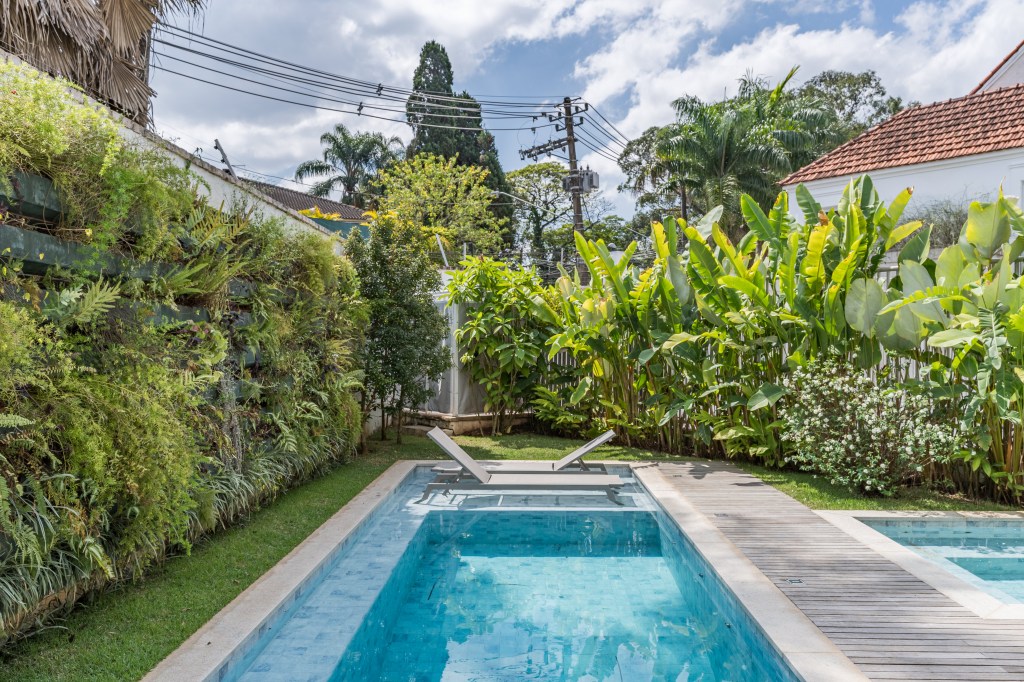 Adega-cristaleira funciona como divisória em área social de casa. Projeto de Spaço Interior. Na foto, área externa, piscina, paisagismo.