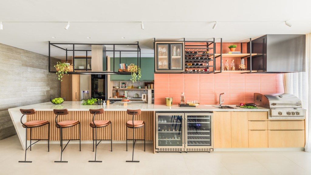 Bancada de lâmina sintetizada integra cozinha e área gourmet neste apartamento