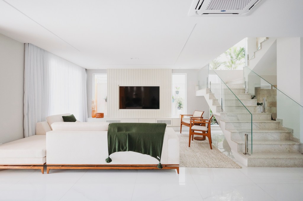 Casa de 800 m² ganha charmoso quarto em estilo boho no sótão. Projeto de Livia Quintella. Na foto, sala de estar, paleta branca, sofá branco, manta verde.