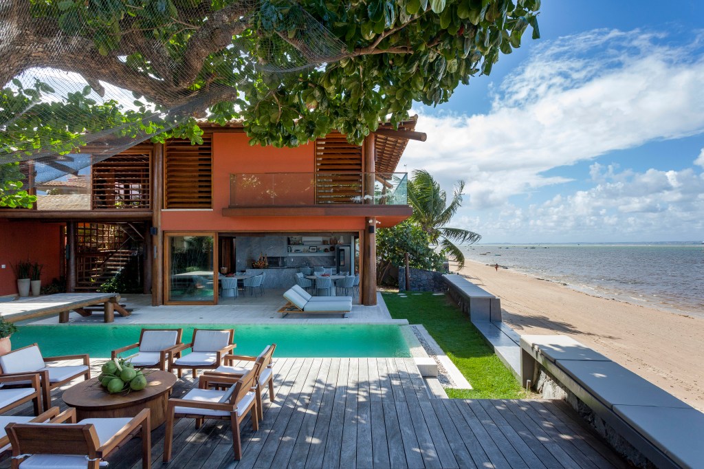 Casa de praia tem estrutura de toras de árvore e pergolados com esteiras em tala de dendê. Projeto de DB Arquitetos. Na foto, piscina.