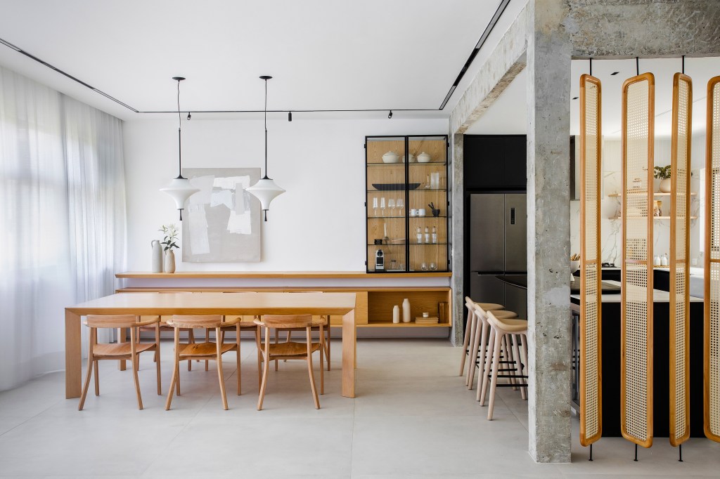 Cozinha preta e branca de apê minimalista tem brises arredondados com palhinha. Projeto de Natália Lemos. Na foto, sala de jantar, mesa de madeira, cristaleira.