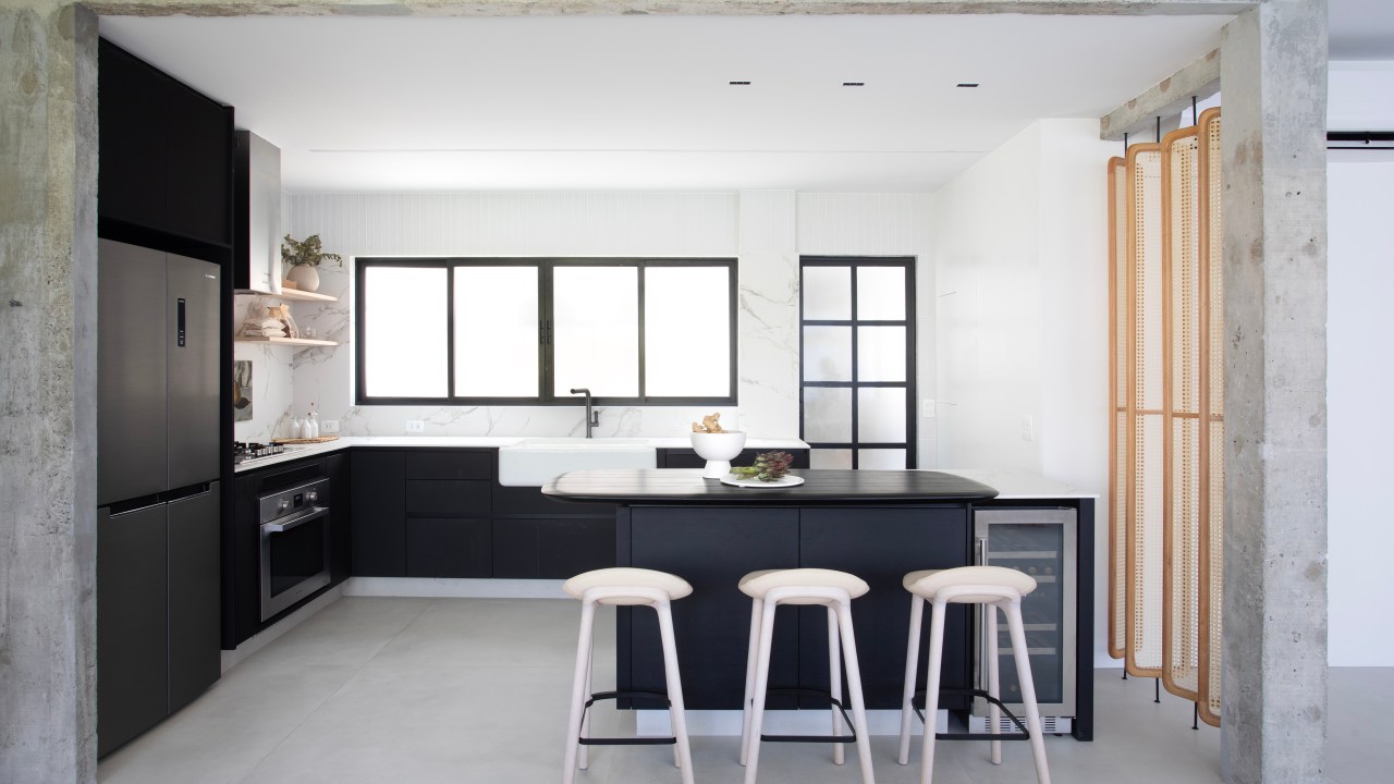 Cozinha preta e branca de apê minimalista tem brises arredondados com palhinha. Projeto de Natália Lemos. Na foto, cozinha, banquetas, viga de concreto.