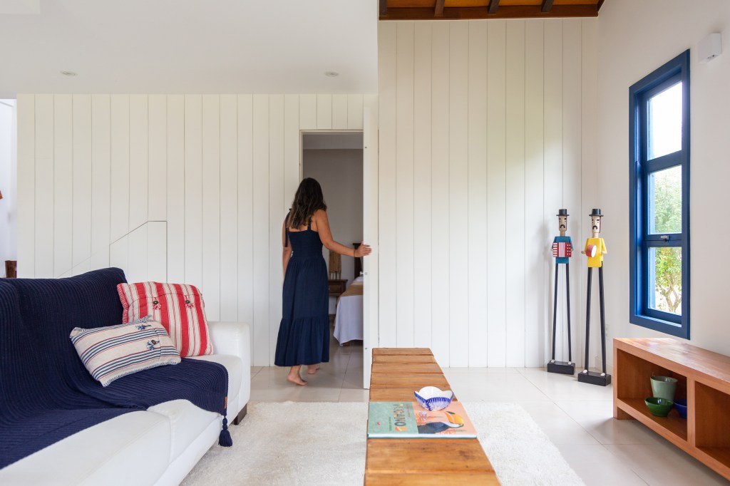 Janelas azuis dão charme a casa de praia em Búzios com suíte térrea escondida por lambris. Projeto de Fernanda Zeitoune. Na foto, quarto, lambri branco.