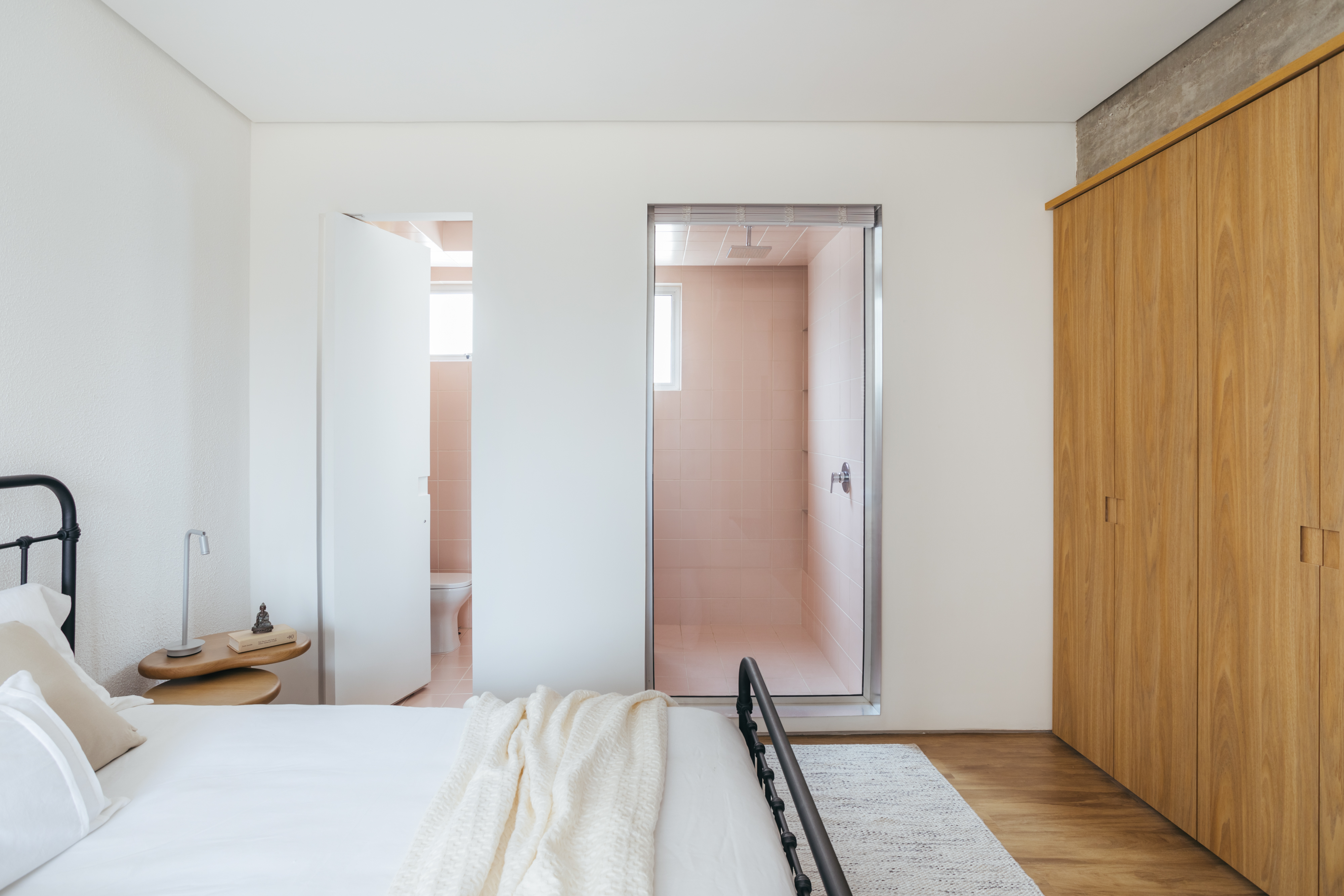 Sala de estar &eacute; ampliada com integra&ccedil;&atilde;o ao quarto, de OCCA+ Arquitetura. Na foto, quarto com vista para o banheiro rosa.