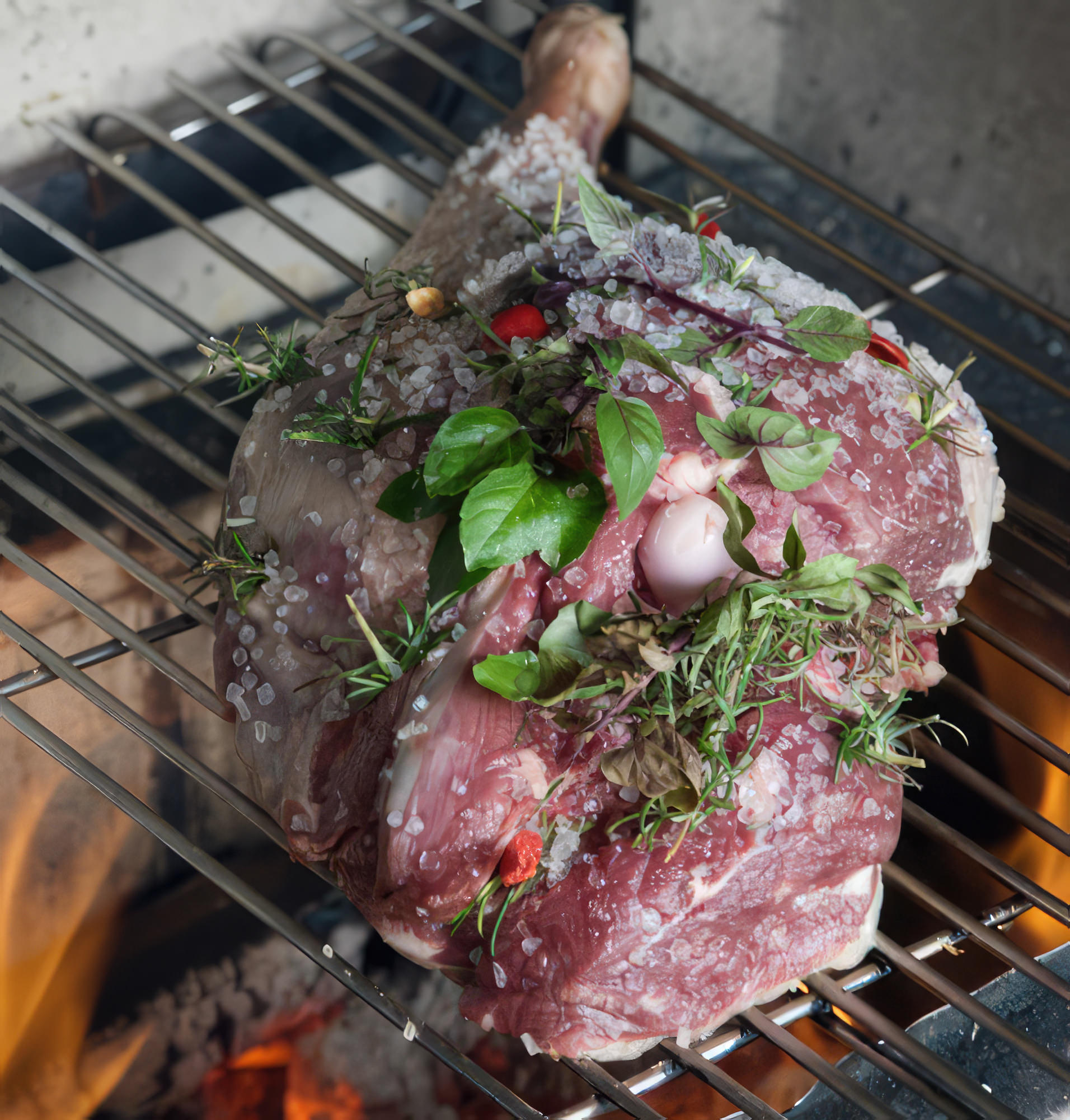 A imagem mostra Istv&aacute;n Wessel, um renomado churrasqueiro, envolvido na prepara&ccedil;&atilde;o do pernil de cordeiro. Ele est&aacute; utilizando alho, alecrim e manjeric&atilde;o frescos para temperar a carne, que &eacute; cuidadosamente disposta na grelha da churrasqueira. O ambiente reflete uma atmosfera t&iacute;pica de um churrasco ao ar livre.